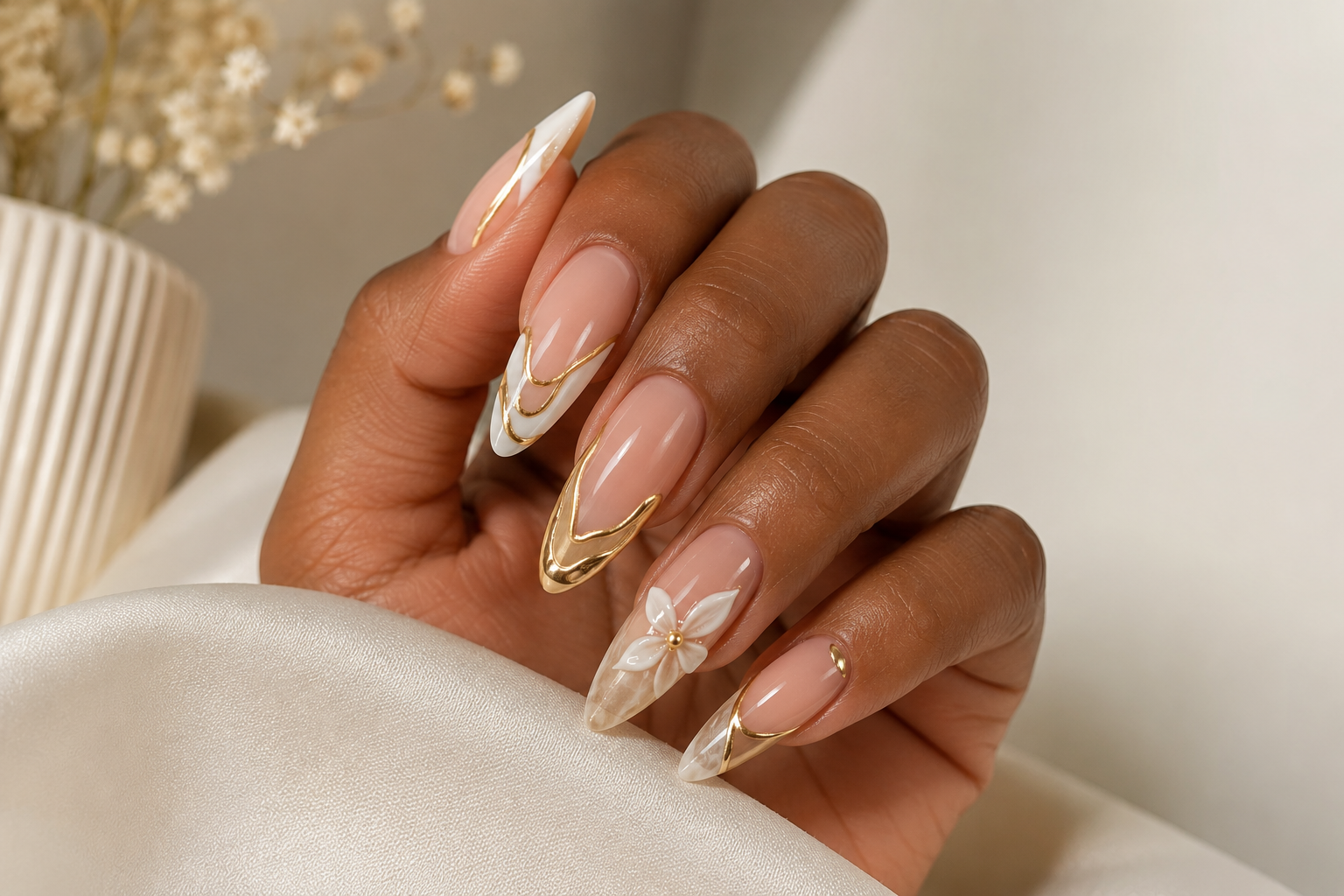 Elegant nude almond nails with gold swirls and white floral details